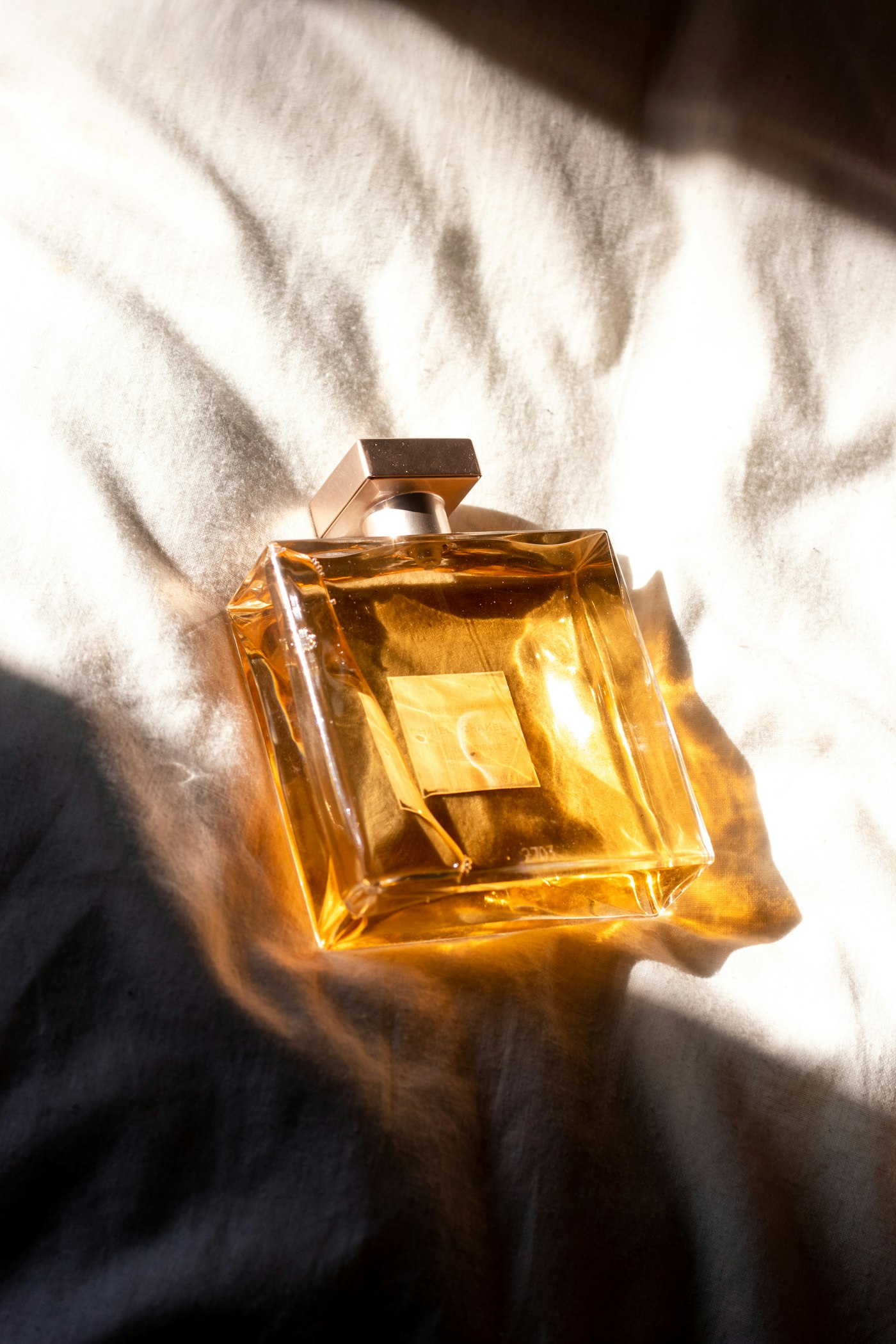 Amber perfume bottle catching the light on linen